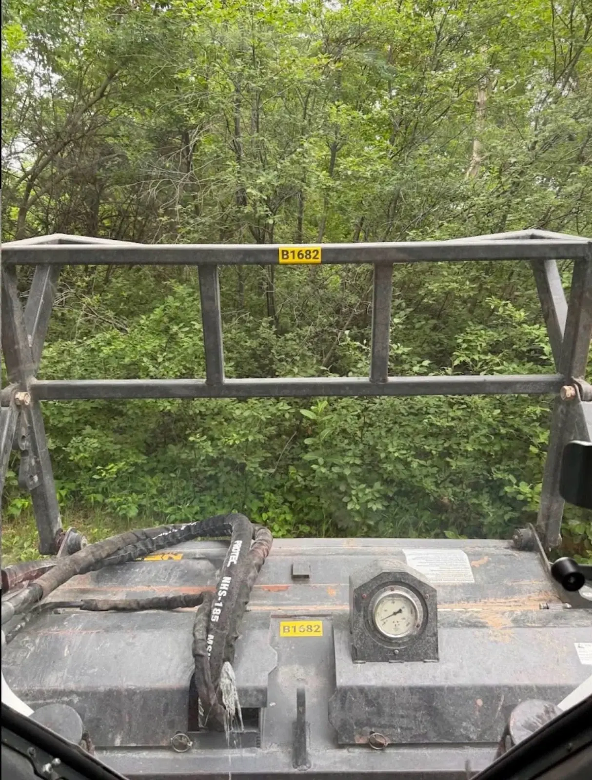 View of a forestry mulching head facing wooded vegetation